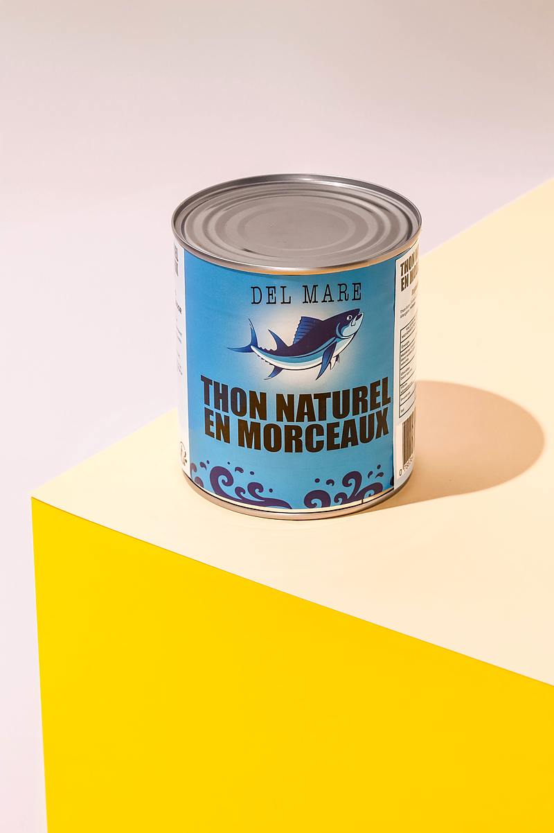 Boîte 4/4 de thon naturel en morceaux, étiquette bleue Del Mare, posée sur un plan jaune